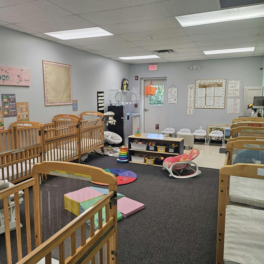 A brightly lit childcare room with multiple wooden cribs