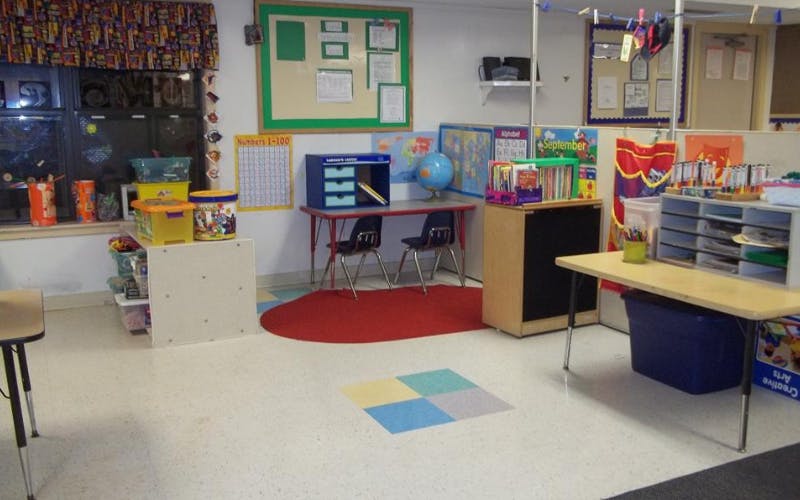 Empty classroom with small tables, chairs, and learning materials