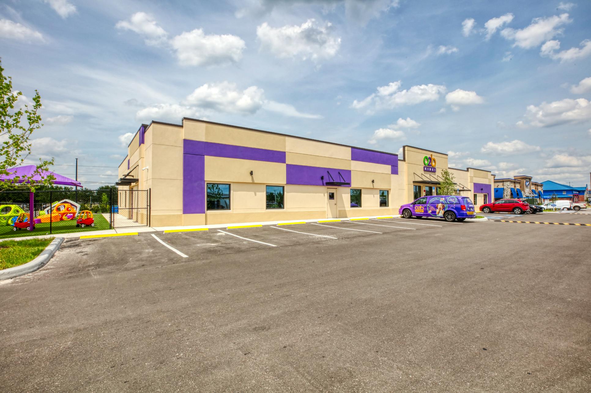 Tan and purple building with a parking lot and playground