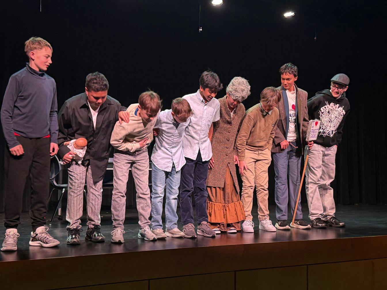 Group of teens and children bowing on a stage