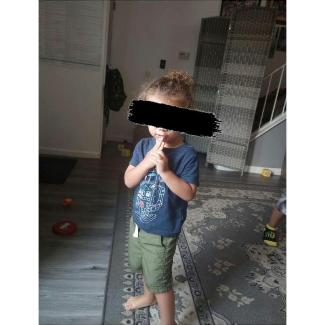 Child standing with fingers to mouth