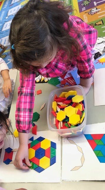 Child creating a colorful geometric pattern with blocks