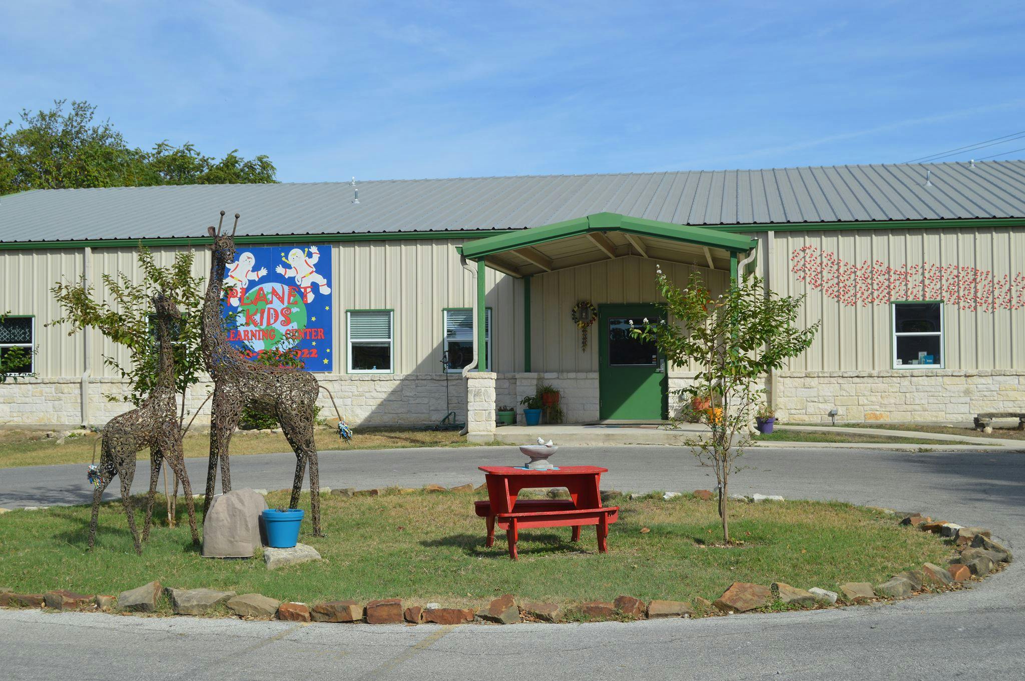 Building exterior with giraffe sculptures and a red picnic table