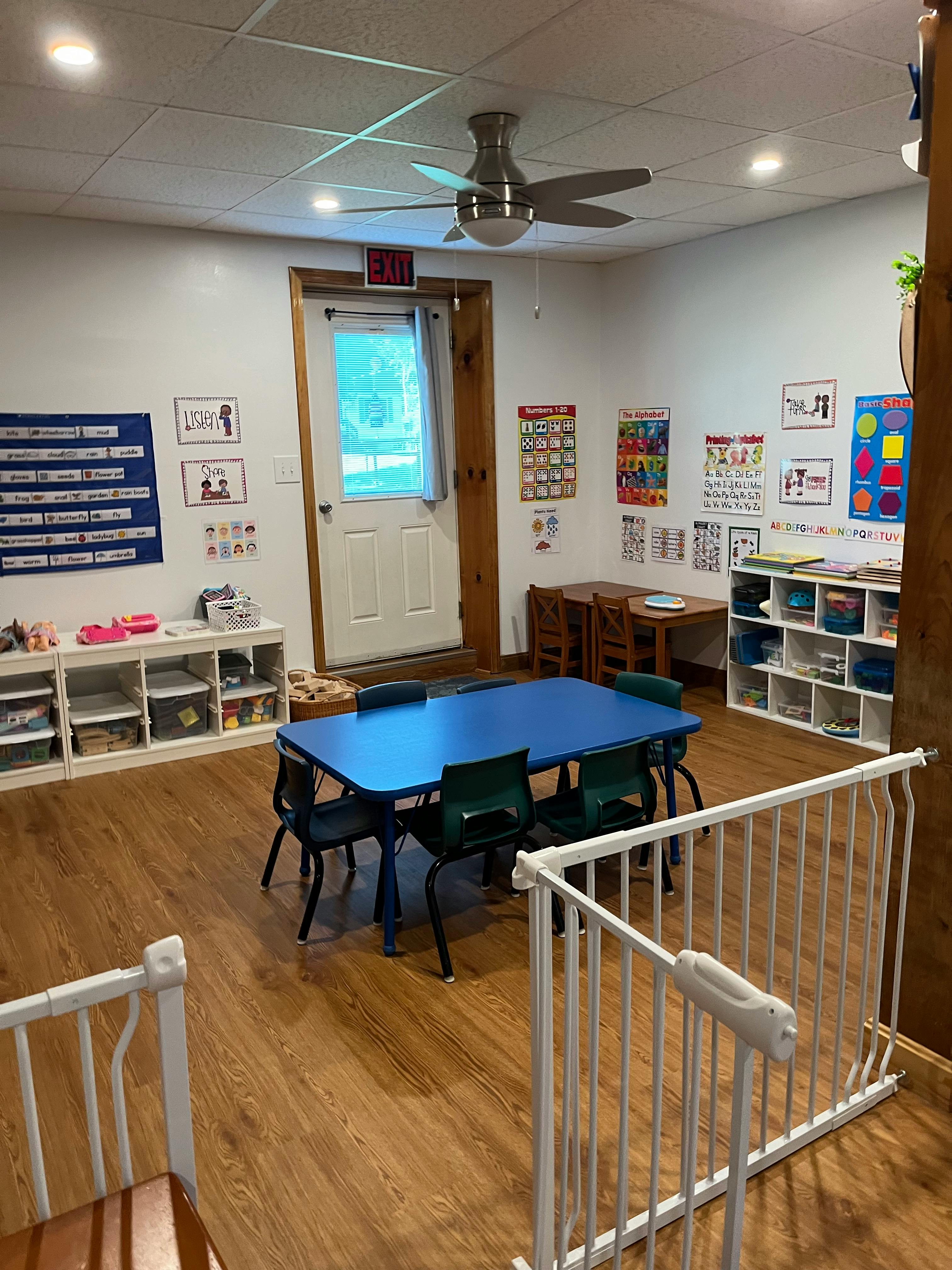 Classroom with a blue table and chairs, shelves, and educational posters