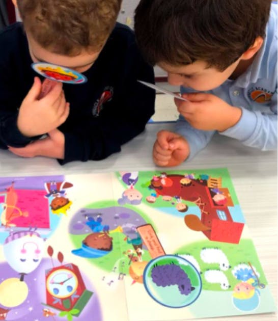 Two children looking at a colorful open book