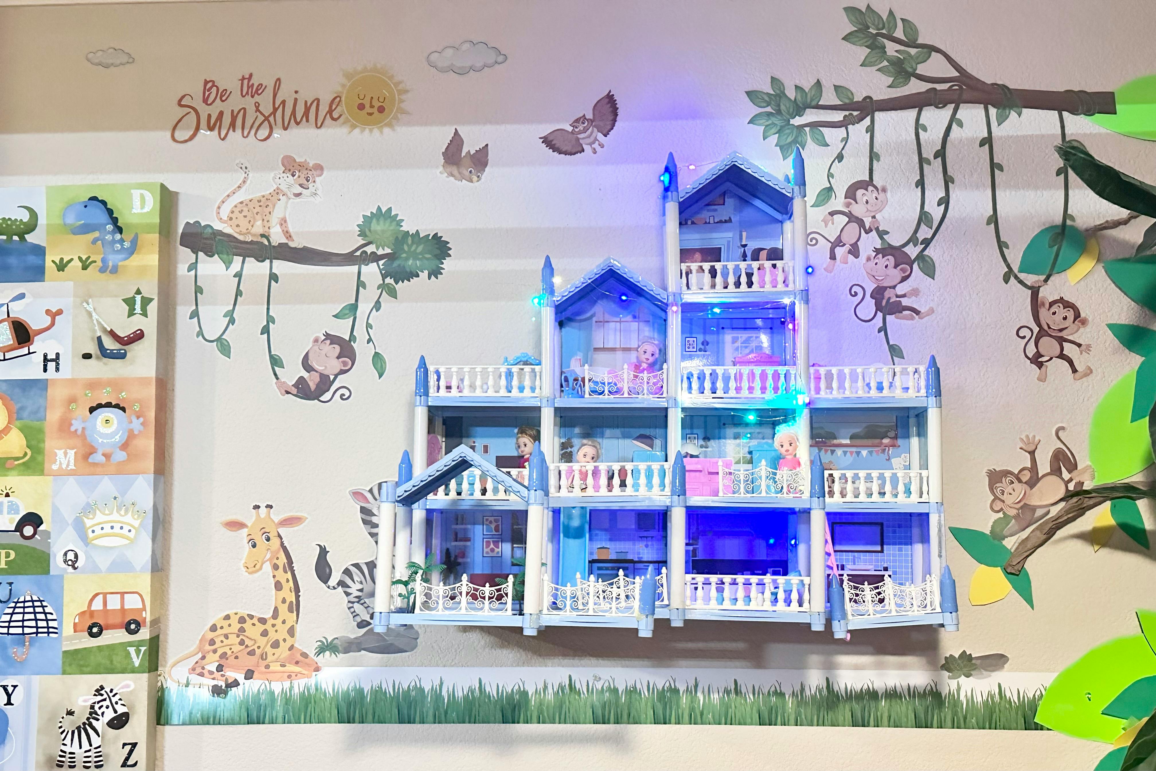 Dollhouse with blue roof and white balconies, surrounded by animal wall decals