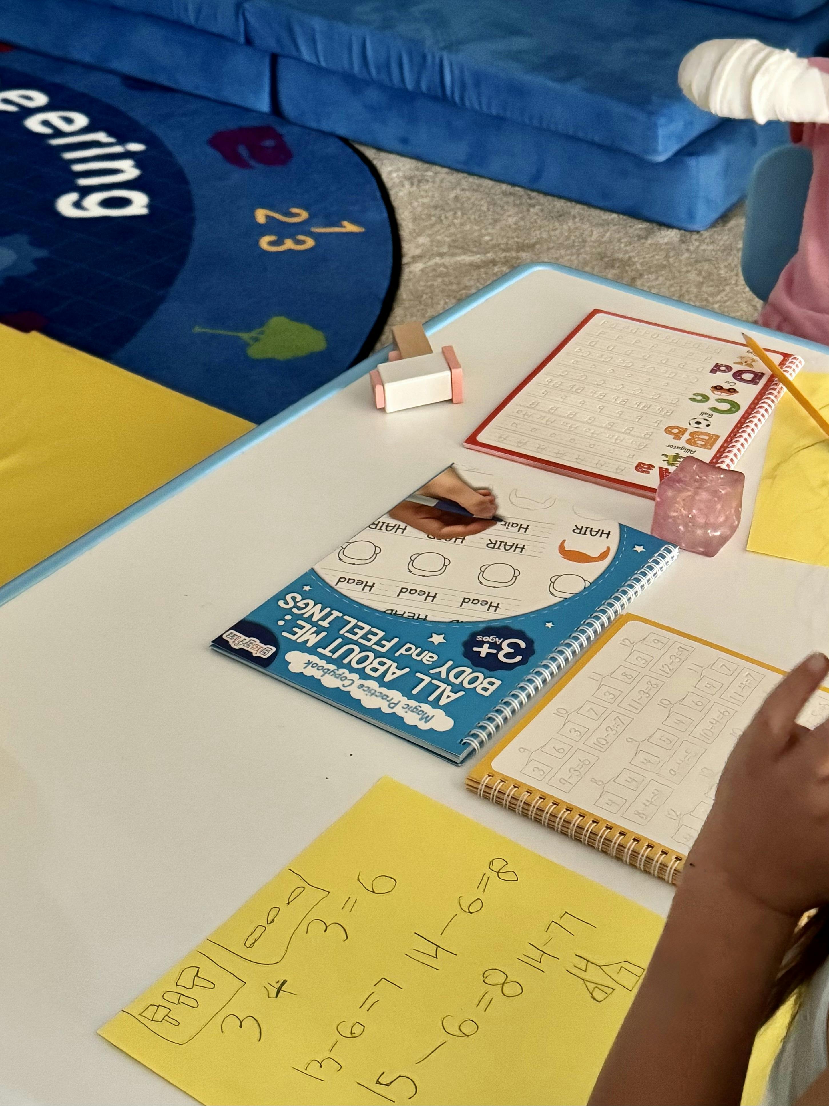 Child practicing handwriting and math at a desk with educational workbooks