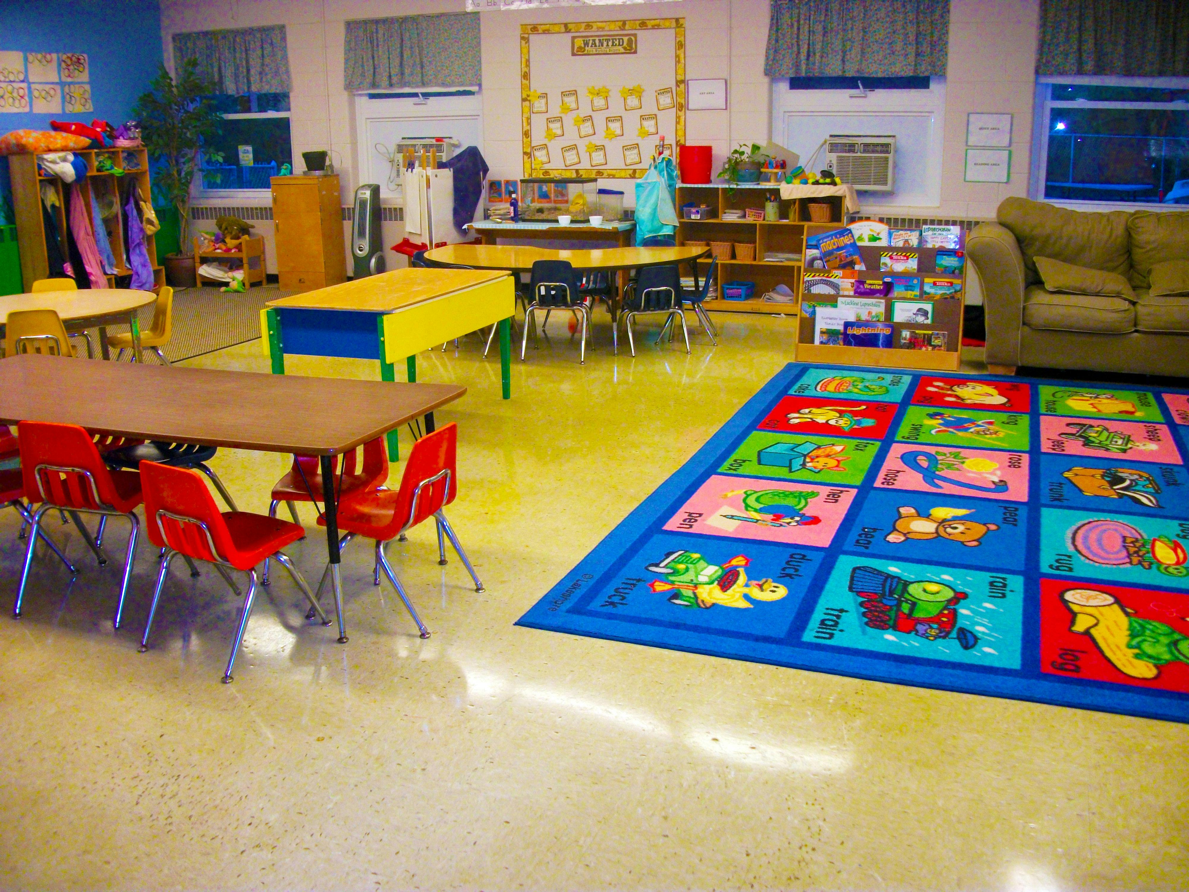 Classroom with tables, chairs, and a colorful rug