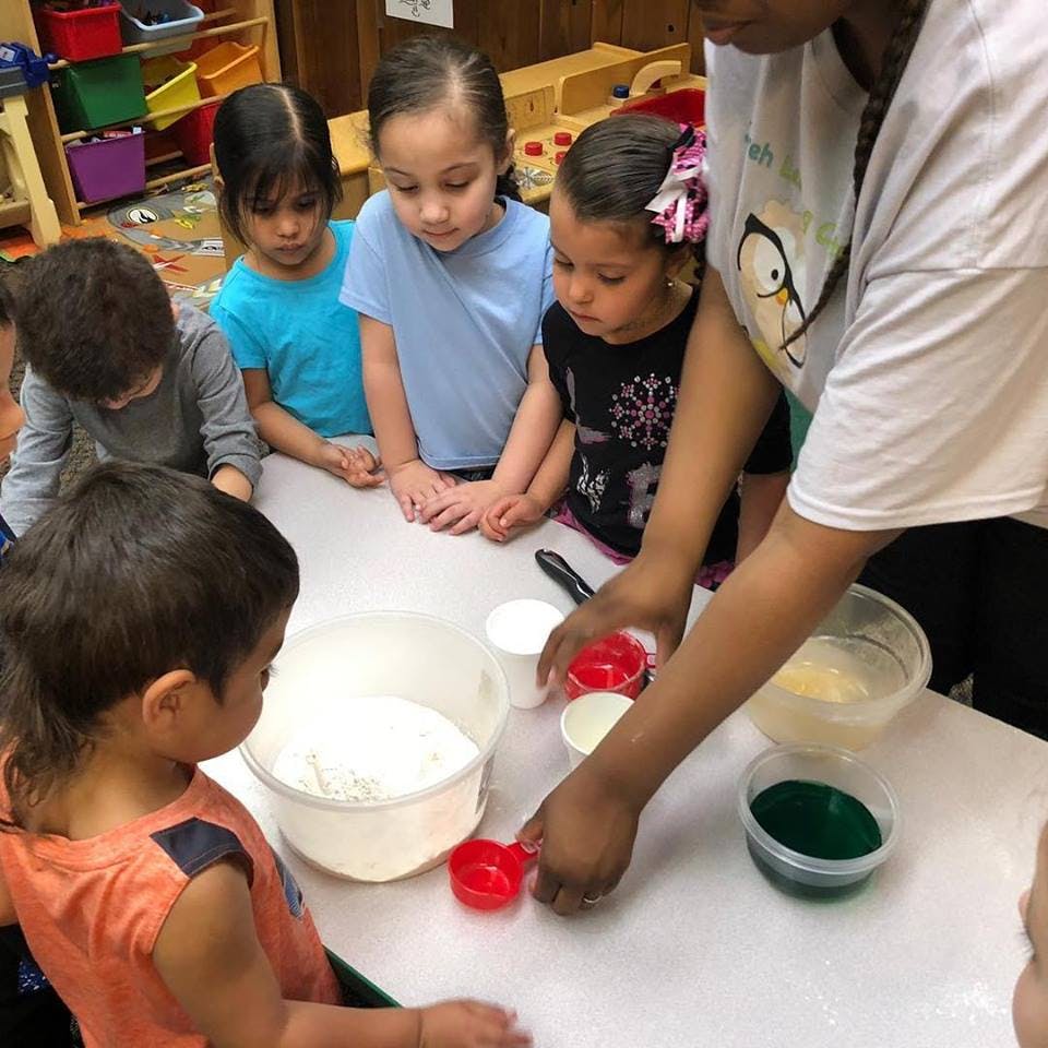 Adult and children gathered around a table with bowls and measuring cups