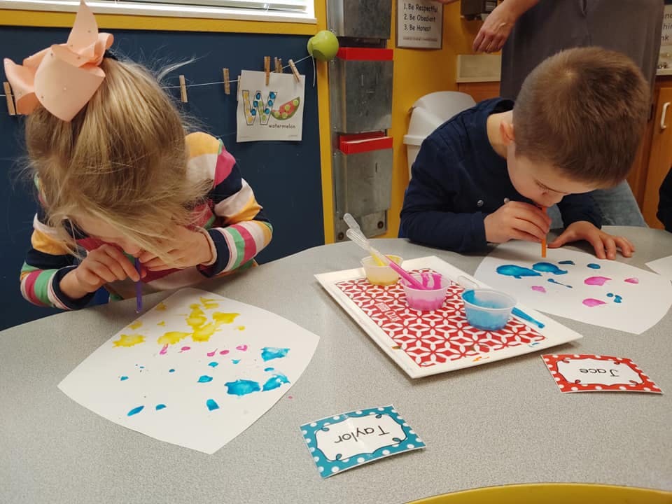 Two children painting at a table
