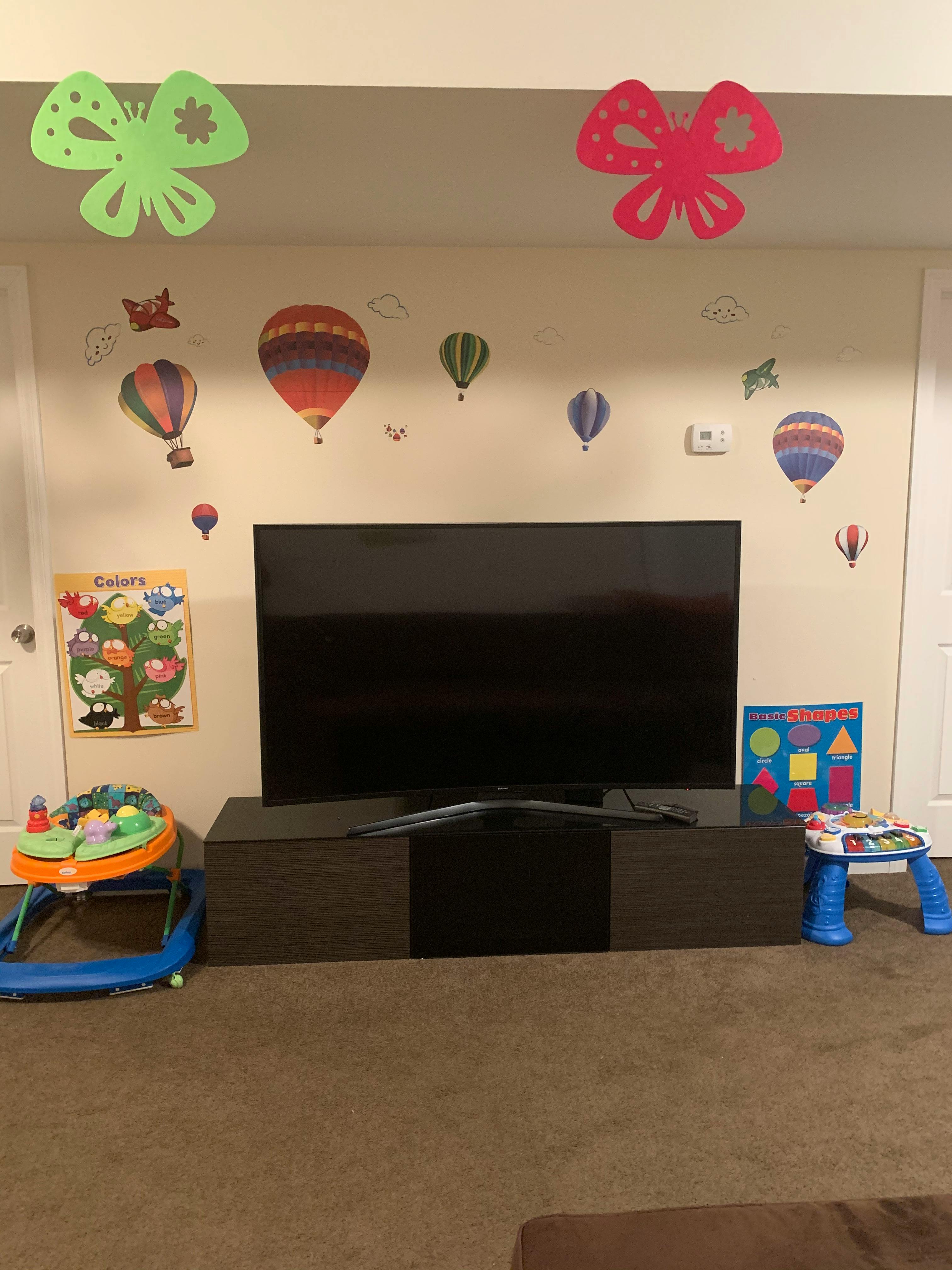 Television on a stand with hot air balloon wall decals and child's toys