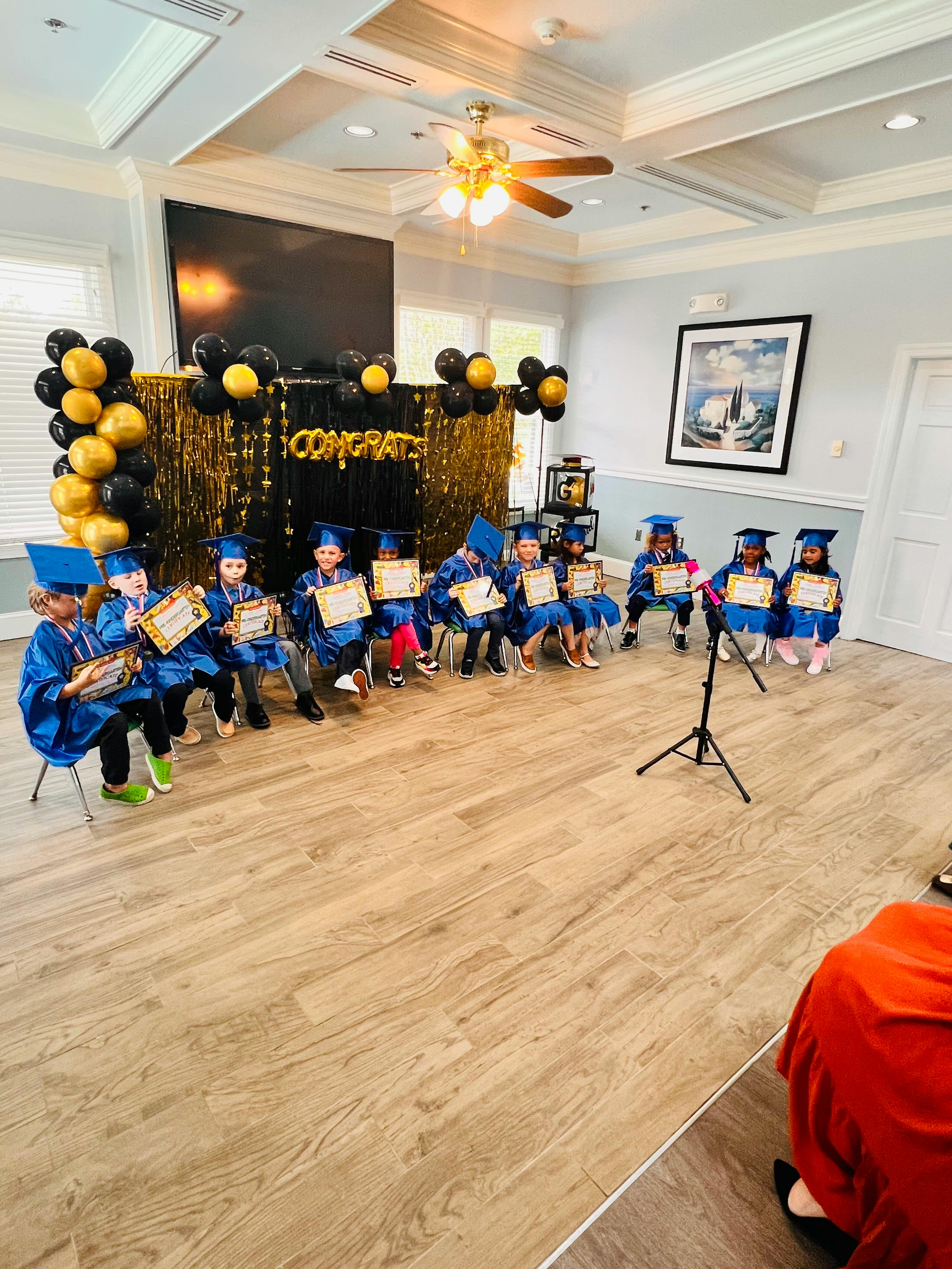 Children in graduation caps and gowns holding certificates