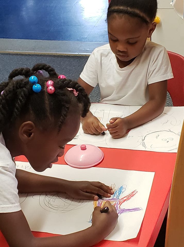 Two children drawing at a table
