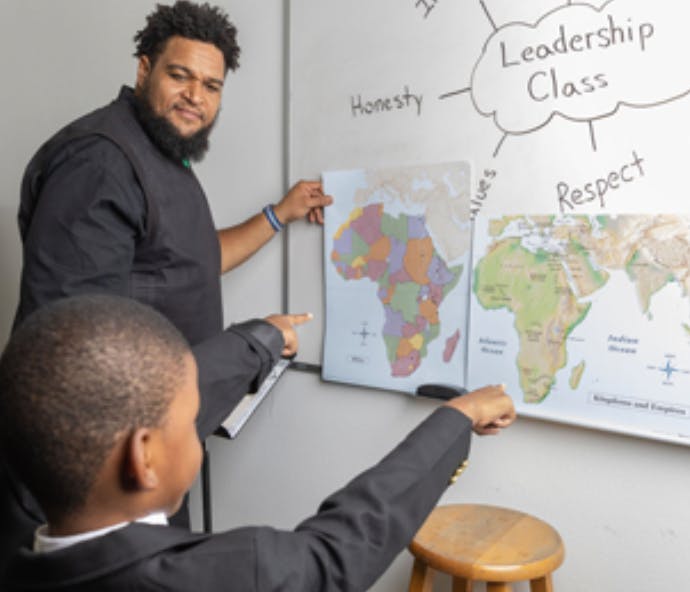 Adult and child pointing at maps on a whiteboard