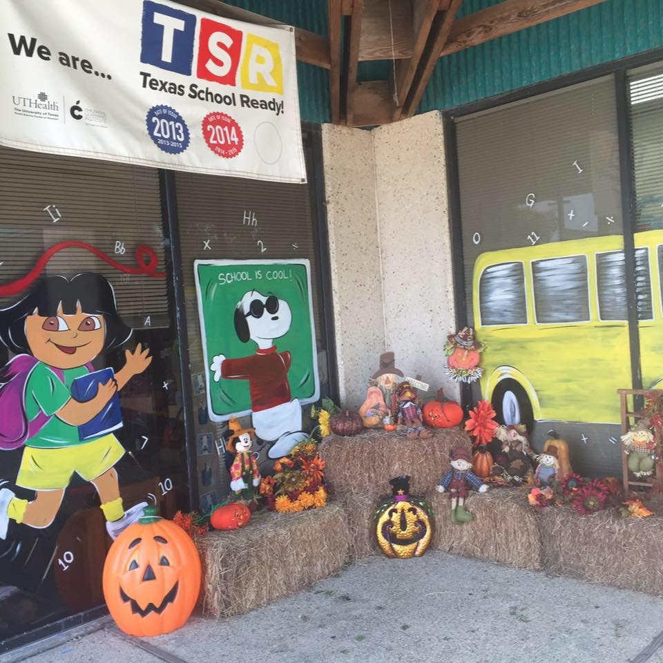 School entrance decorated with cartoon cutouts and hay bales with pumpkins