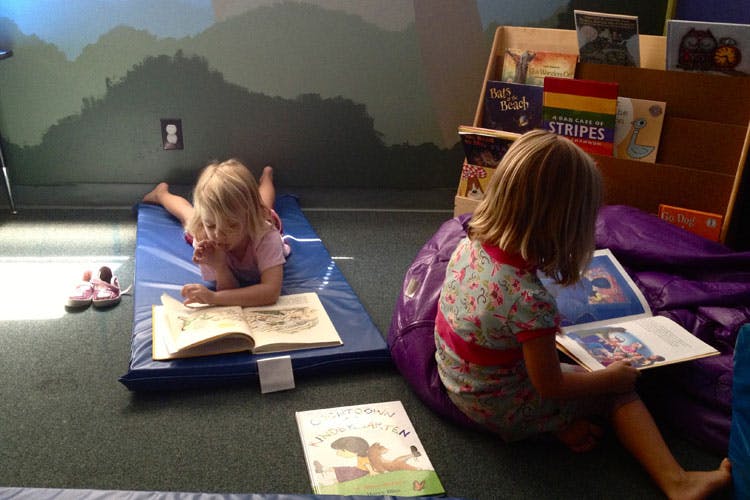 Two children reading books on the floor
