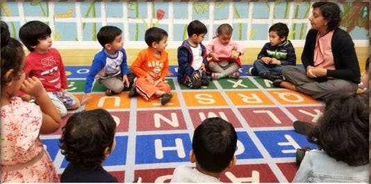 Adult and children sitting on an alphabet mat in a classroom