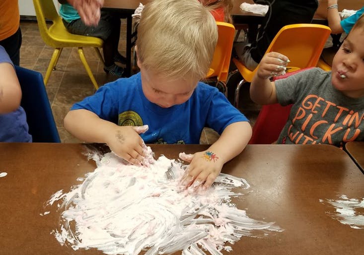 Child playing with white foam on a table