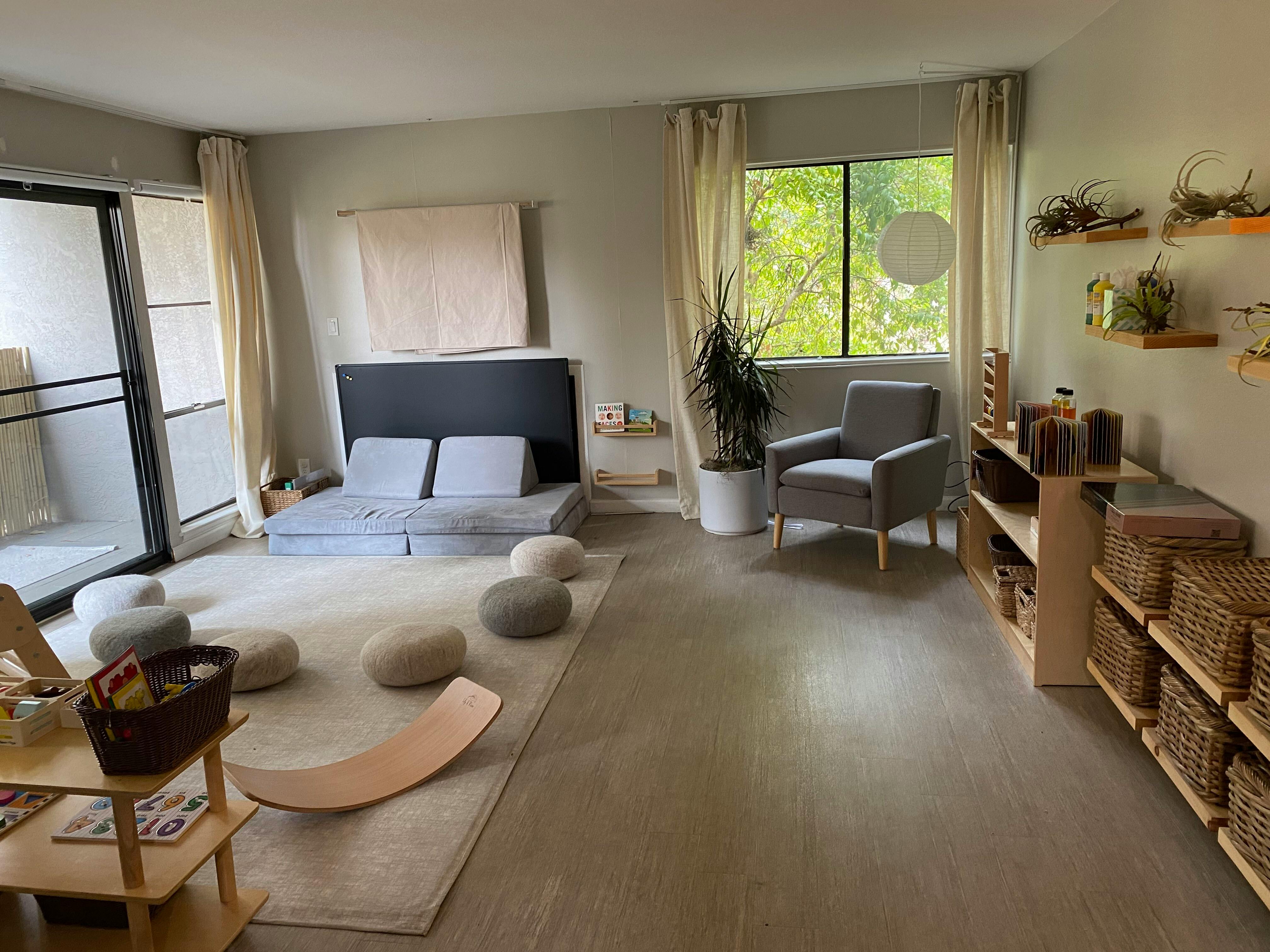 Room with floor cushions, a low sofa, armchair, and shelves with baskets