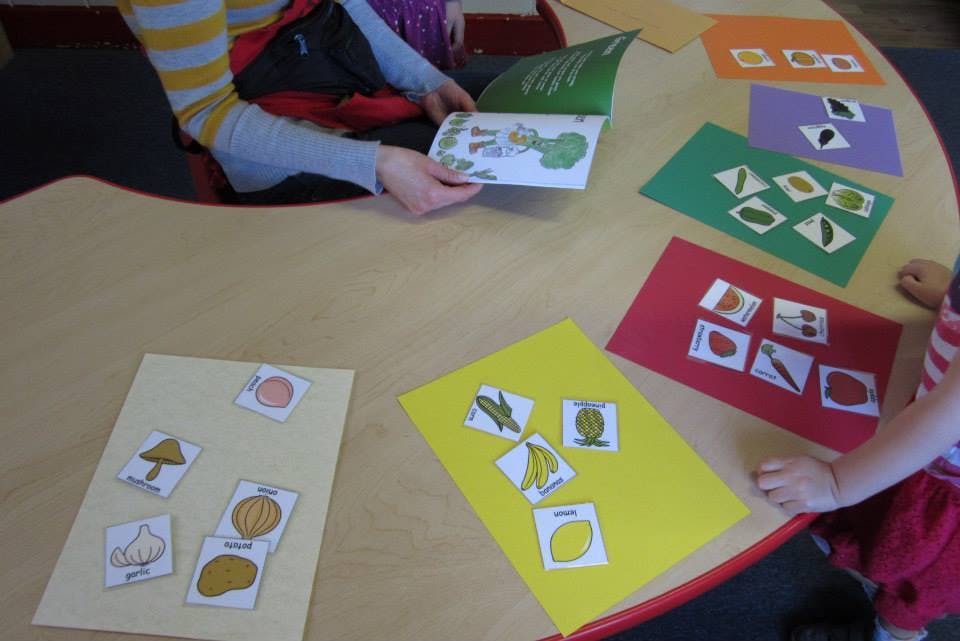 Person and child at a table with cards and a book