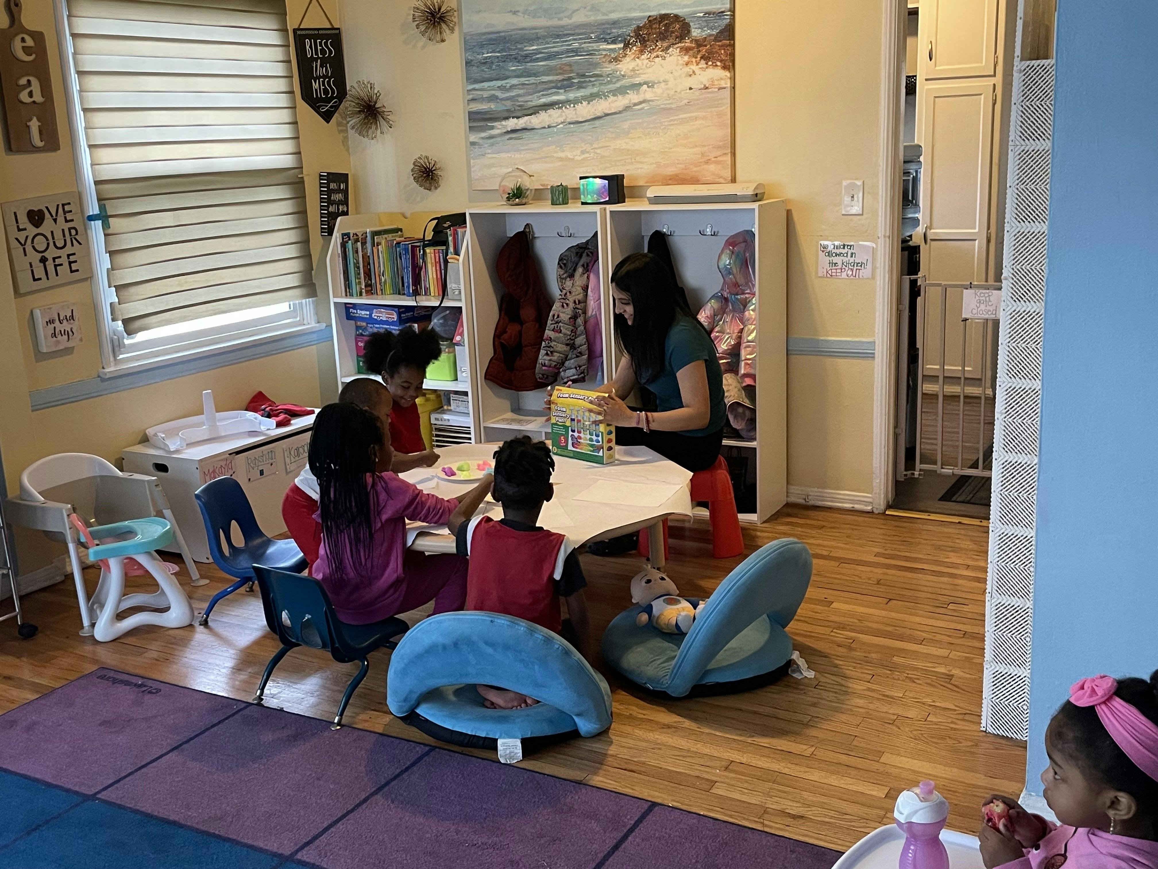 A person helping three children with an activity at a small table