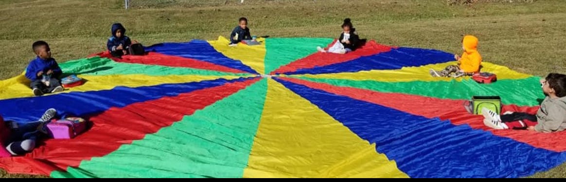 Children sitting on a colorful parachute on the grass