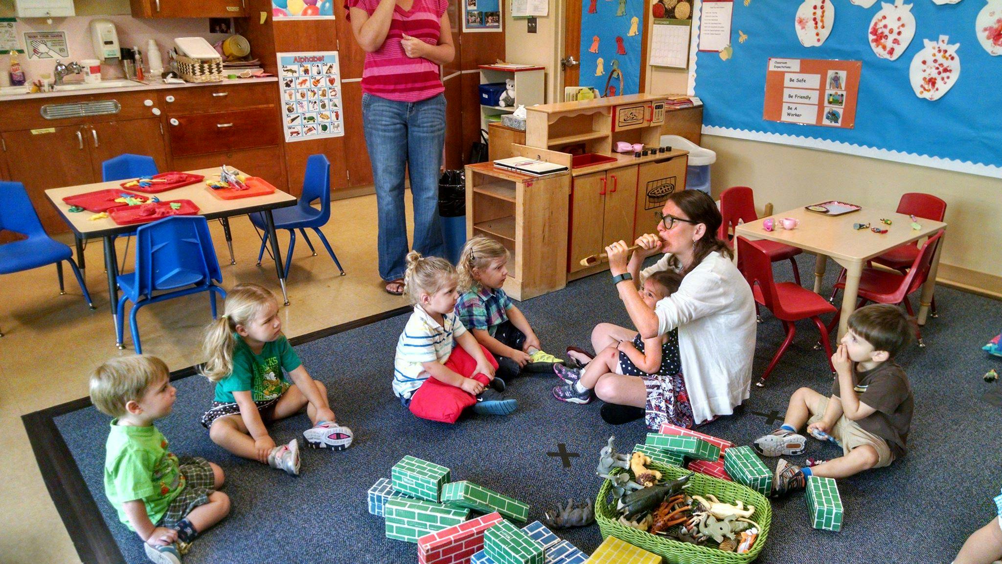 Adults and children sitting on the floor in a classroom