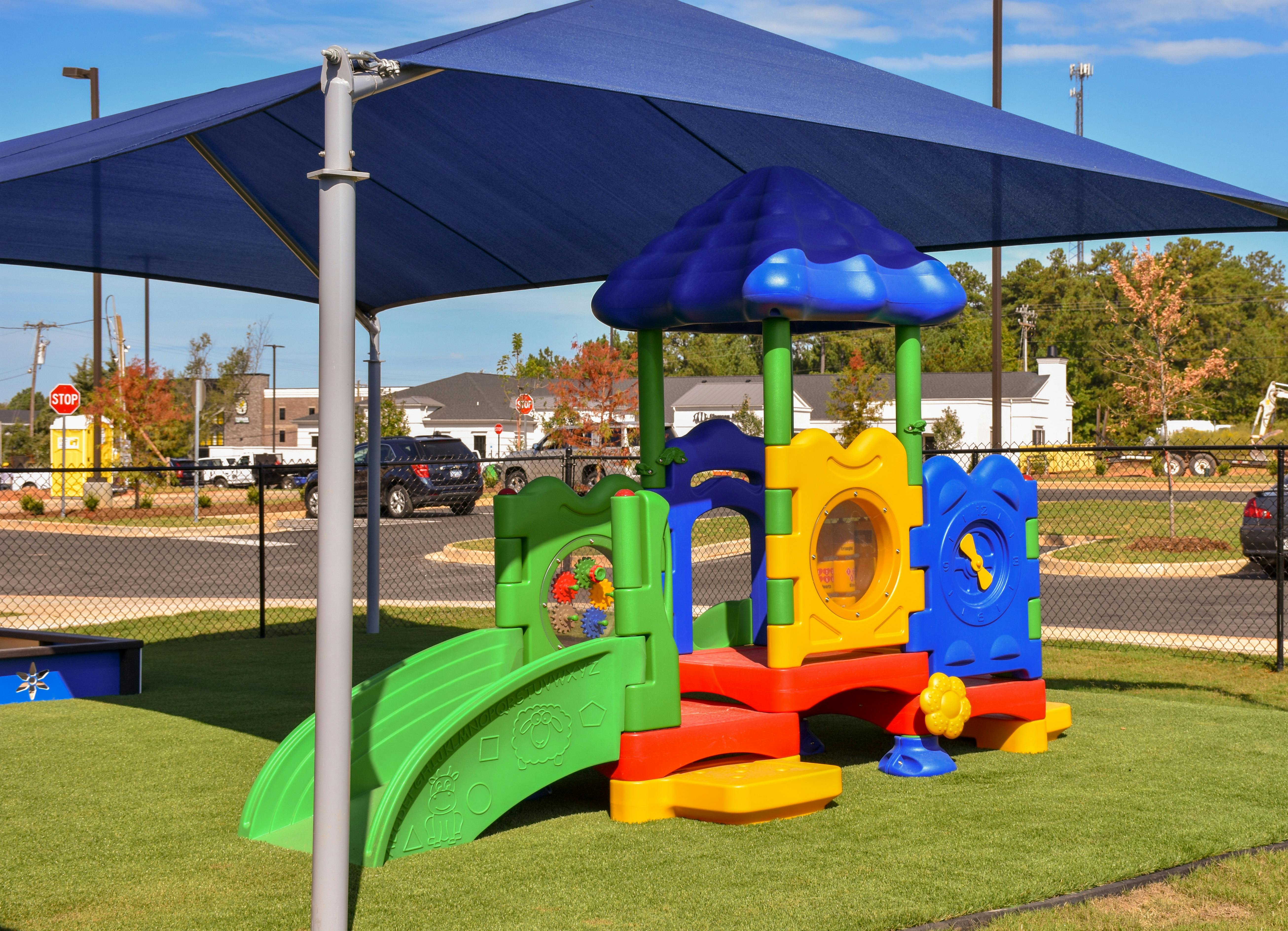 Colorful playground equipment under a blue shade structure