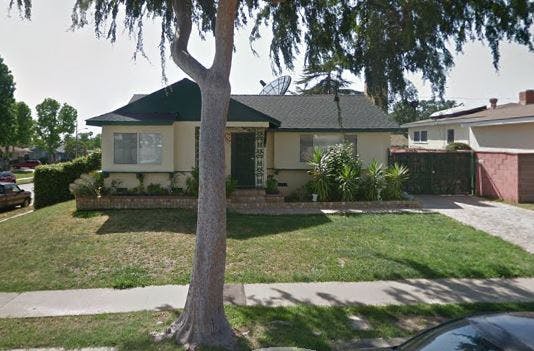 Single-story house with a green lawn and a tree in the foreground