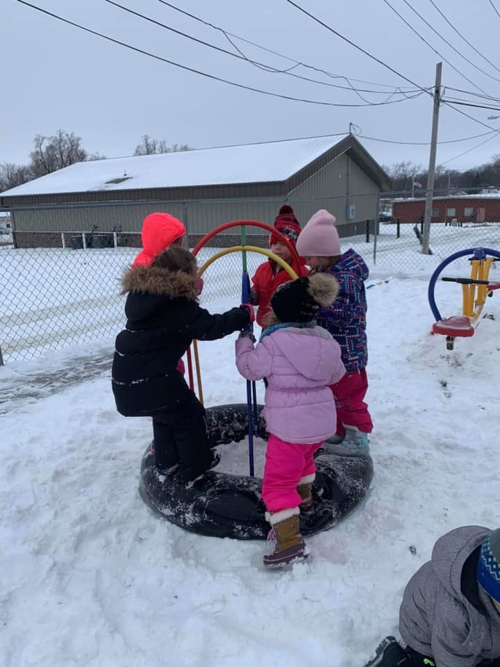 Children playing on a tire swing in the snow