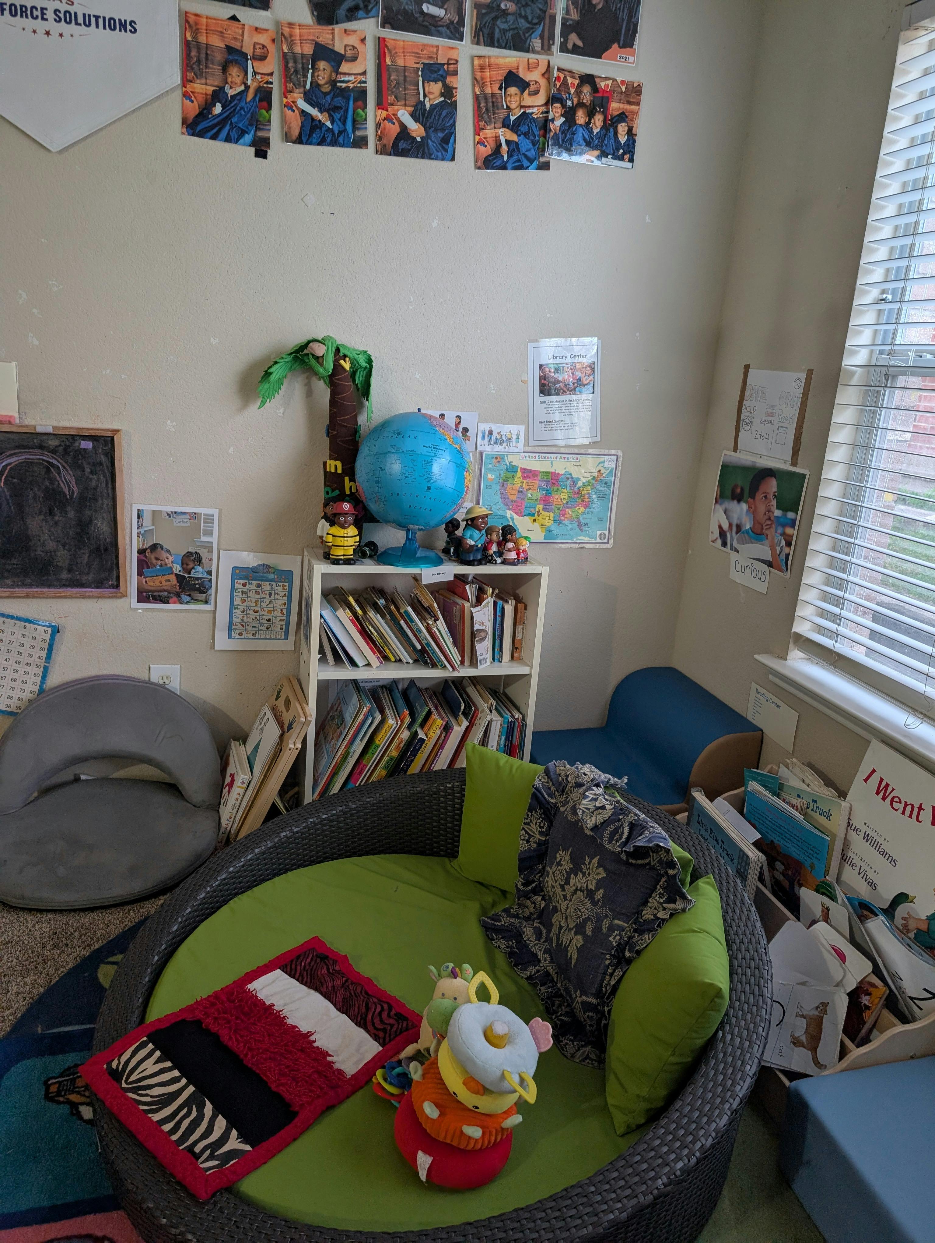 A playroom with child-sized furniture, a bookshelf, and various educational materials