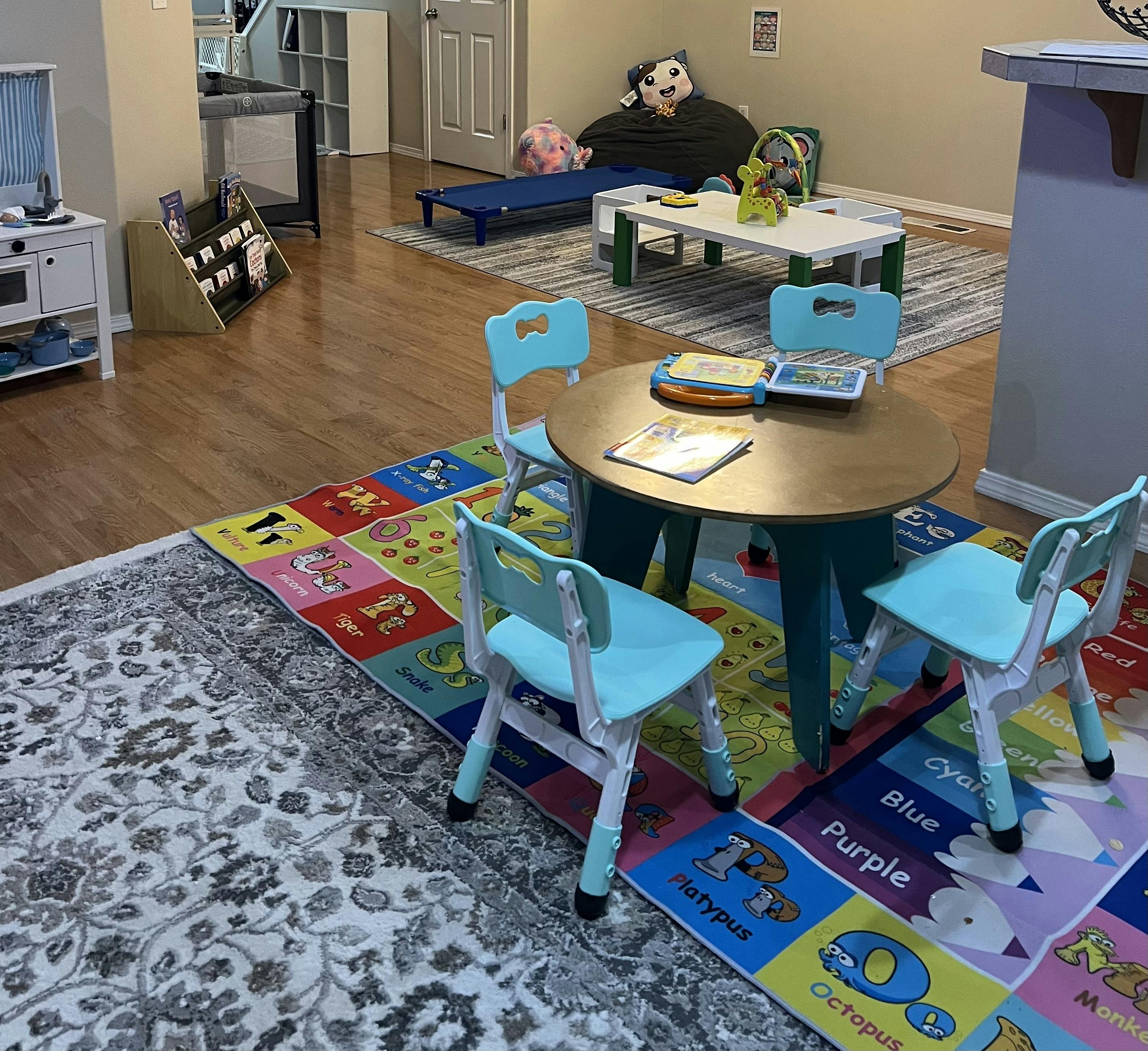 Child's play area with small tables and chairs, and a colorful alphabet rug