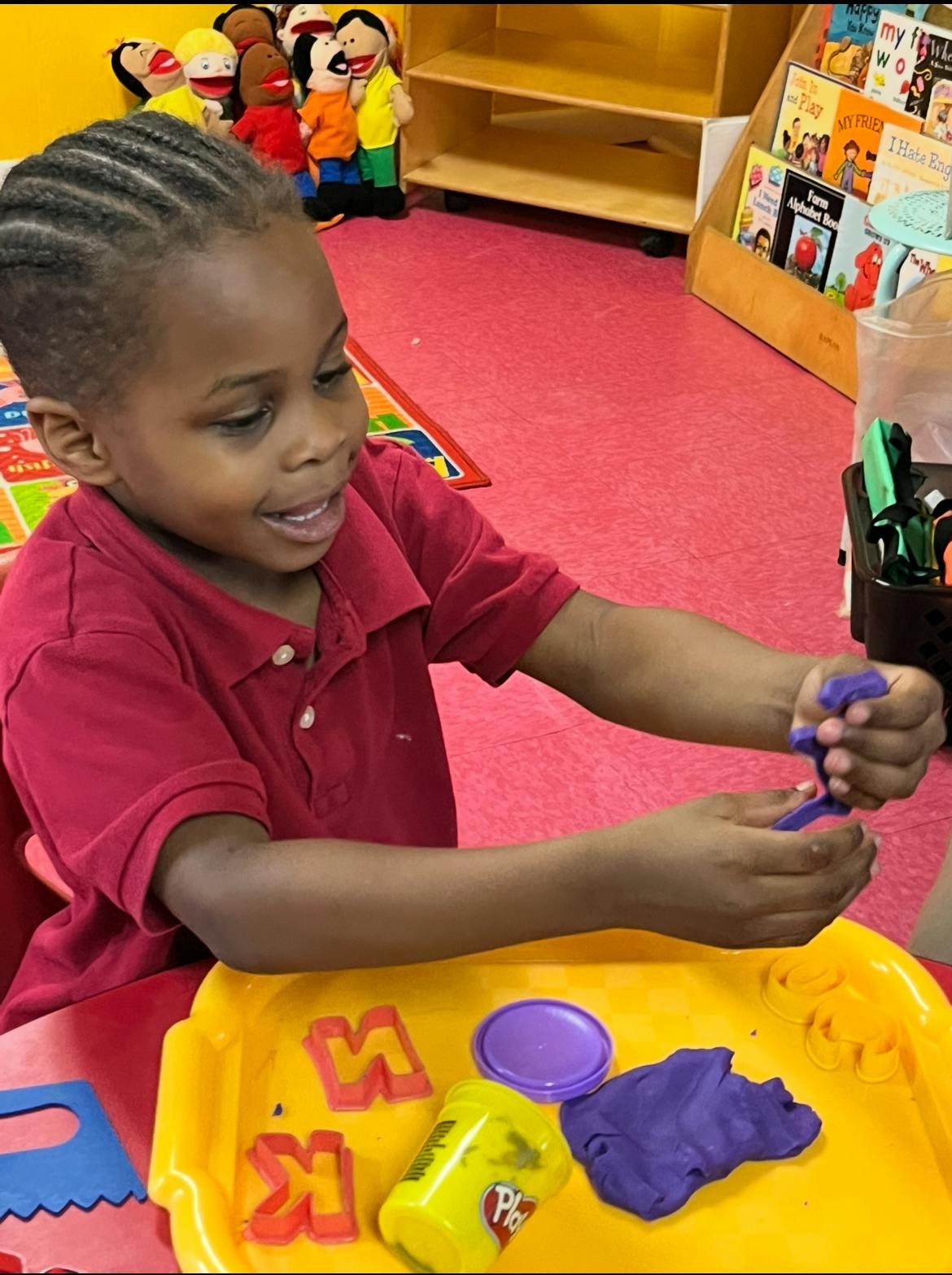 Child playing with purple playdough in a classroom