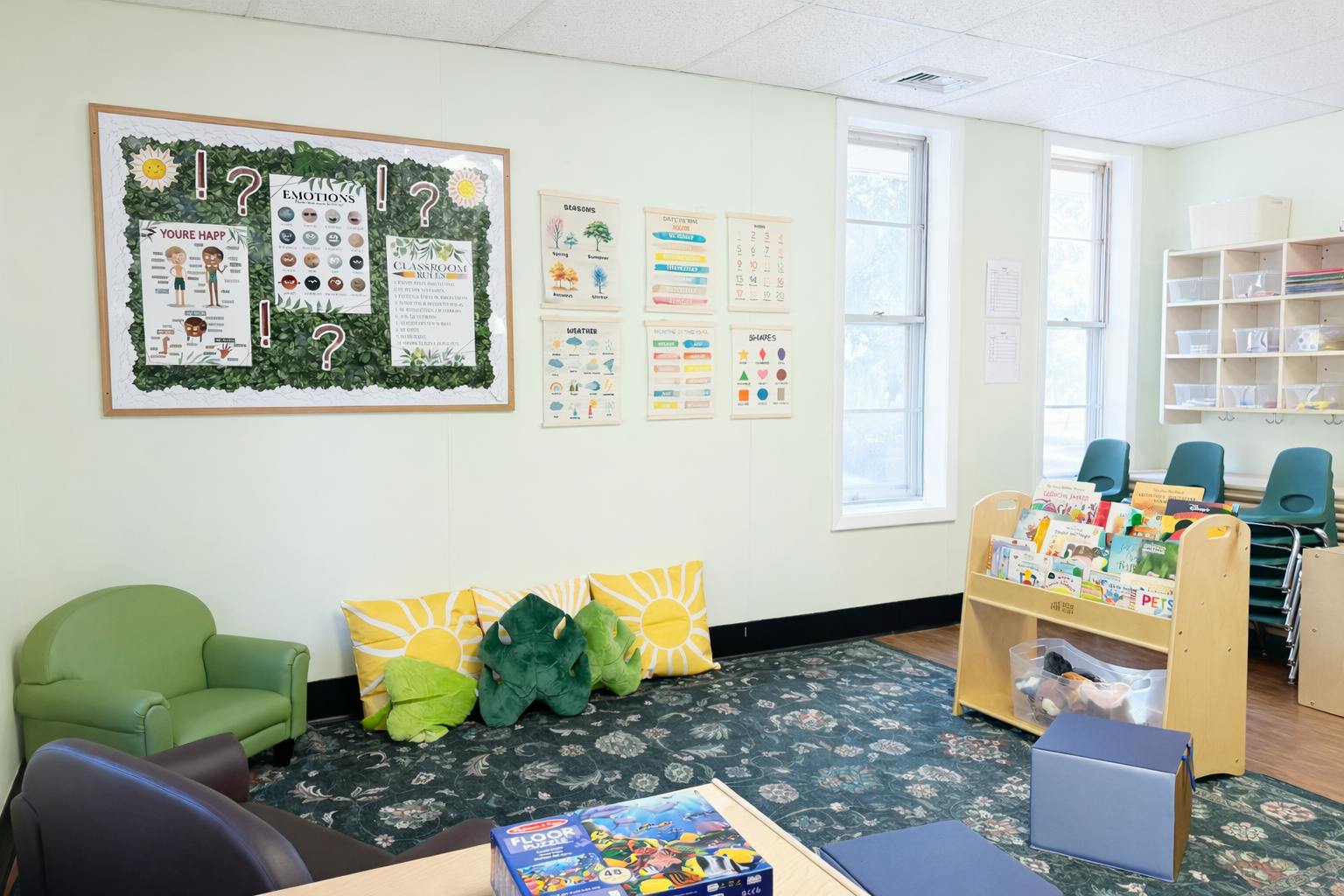 Classroom interior with educational wall posters, books on a shelf, and seating
