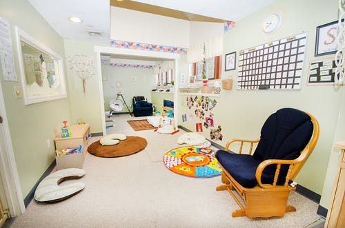 Room with a wooden rocking chair, play mat, and baby items