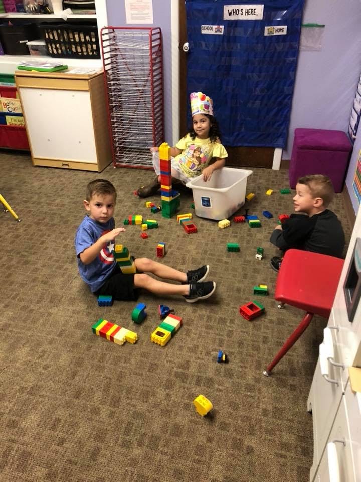 Three children playing with building blocks on the floor