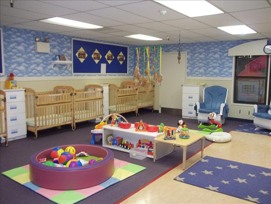 An empty nursery room with cribs, play mat, toys, and baby furniture