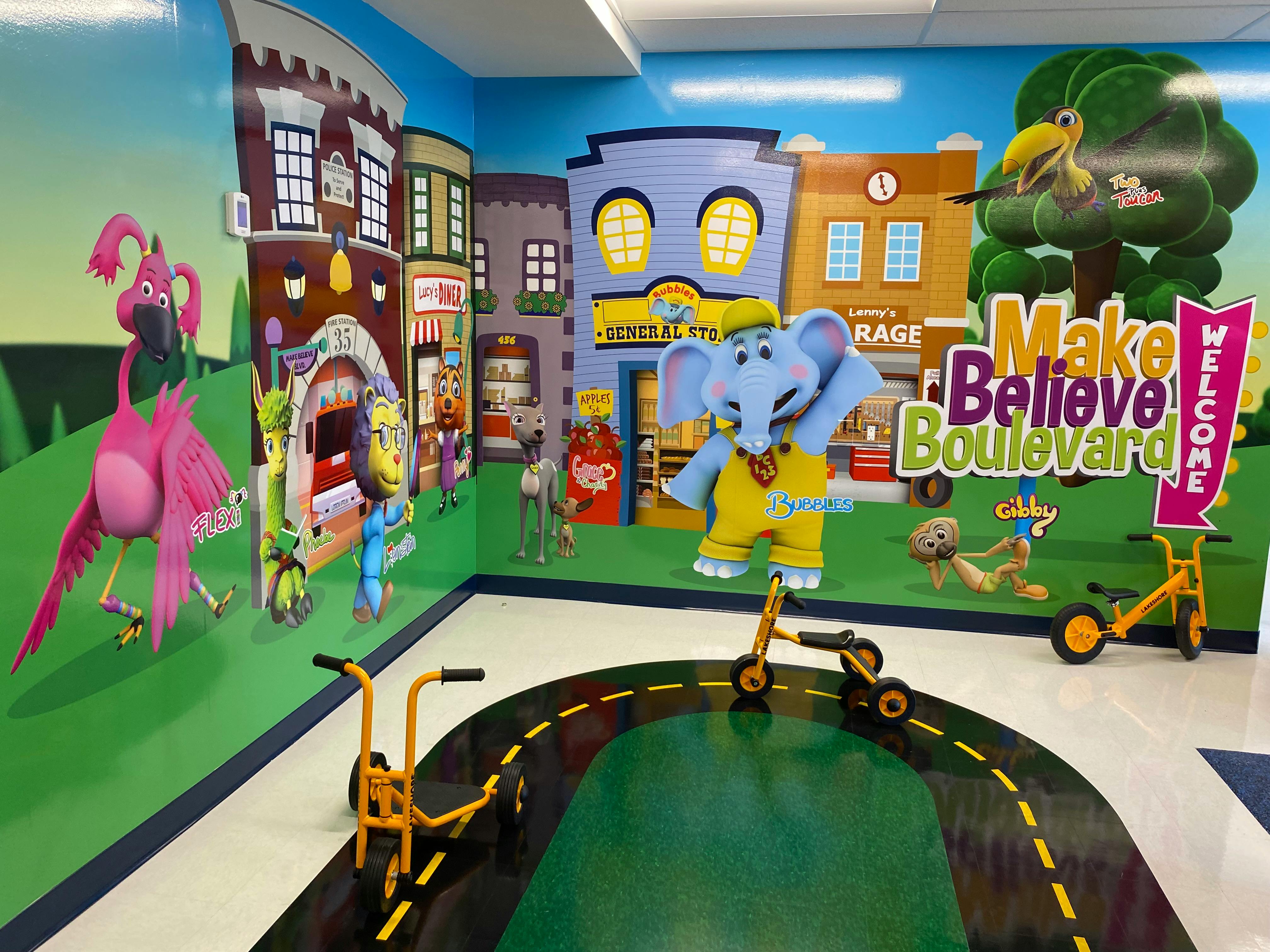 Playroom with cartoon buildings, characters, and a road with toy scooters