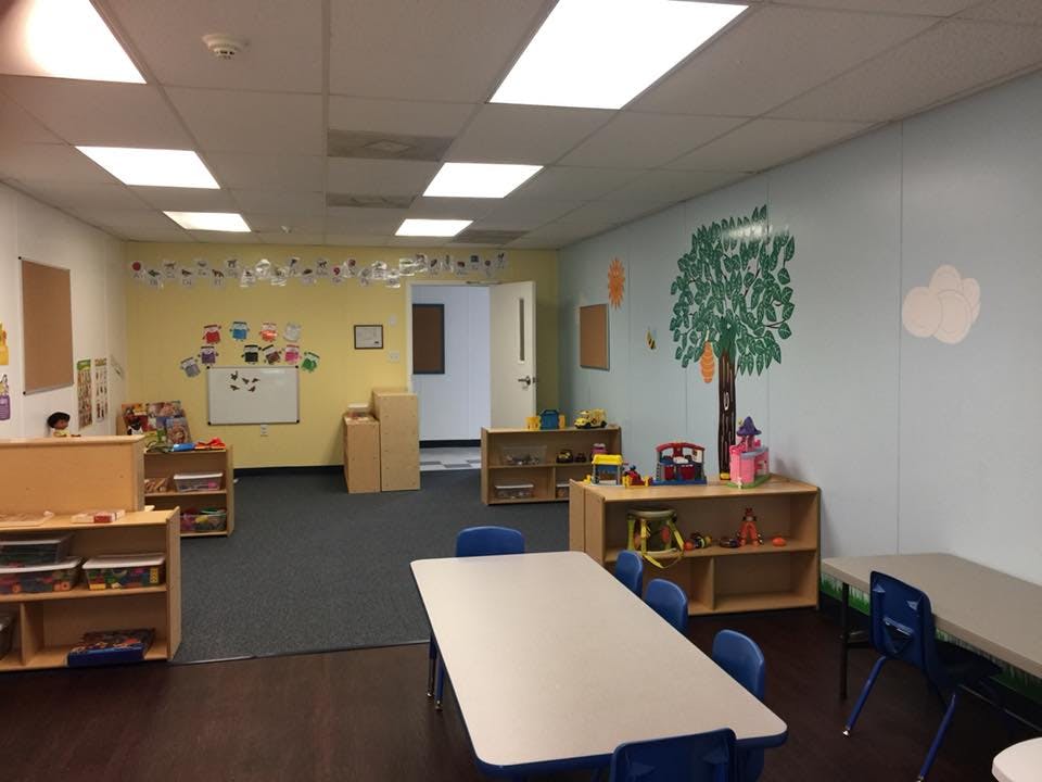Empty classroom with tables, chairs, and shelves with toys