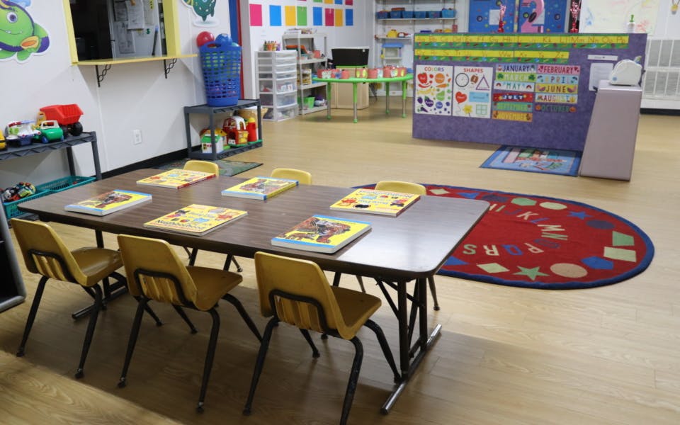 Classroom with a long table and chairs, and a colorful rug