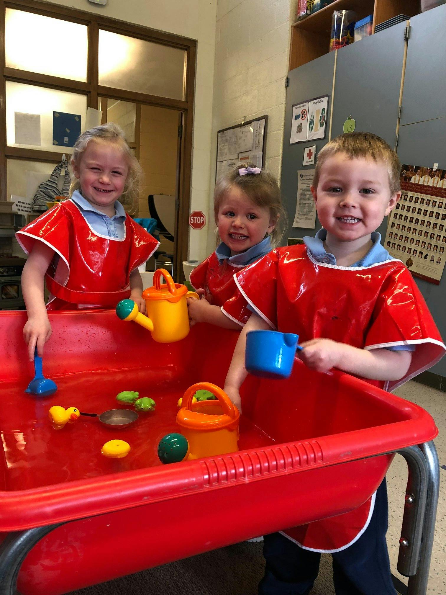 Three children playing in a water table with toys