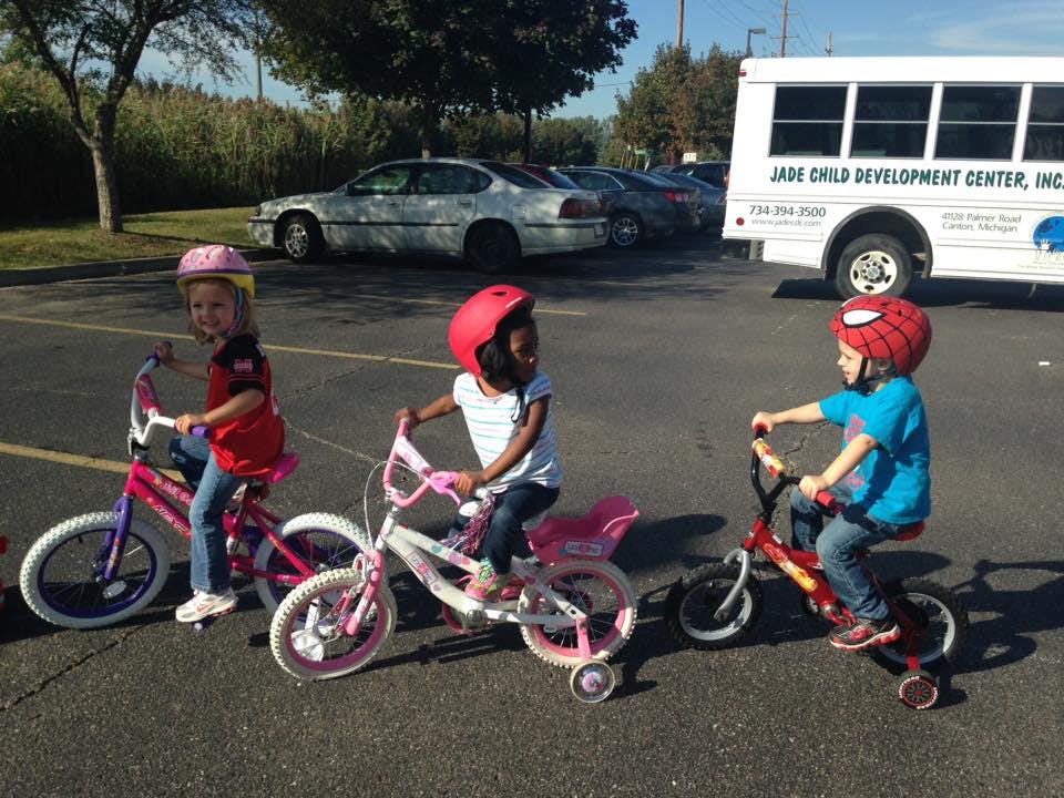 Three children wearing helmets riding bicycles