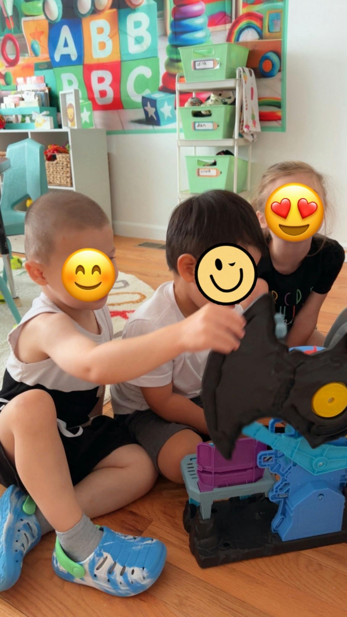 Three children playing with toys on a wooden floor