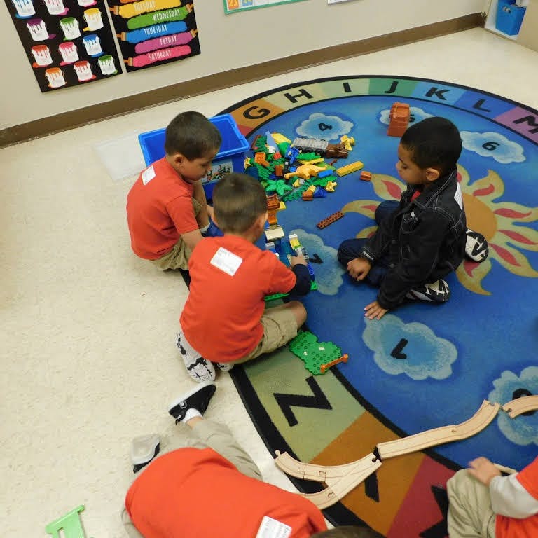 Children playing with toys on a rug in a classroom