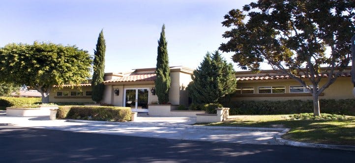 Building with a tiled roof and tall trees in front