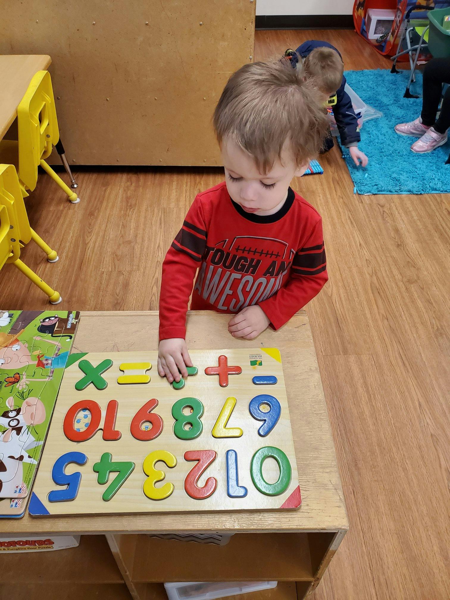 Child playing with a colorful number and math symbol puzzle