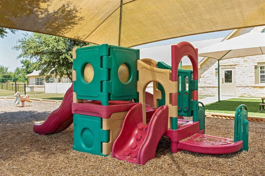 Playground structure with slides and climbing areas under a shade