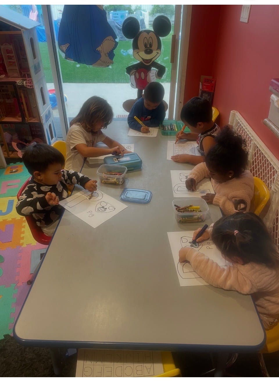 Children drawing and coloring at a table in a classroom