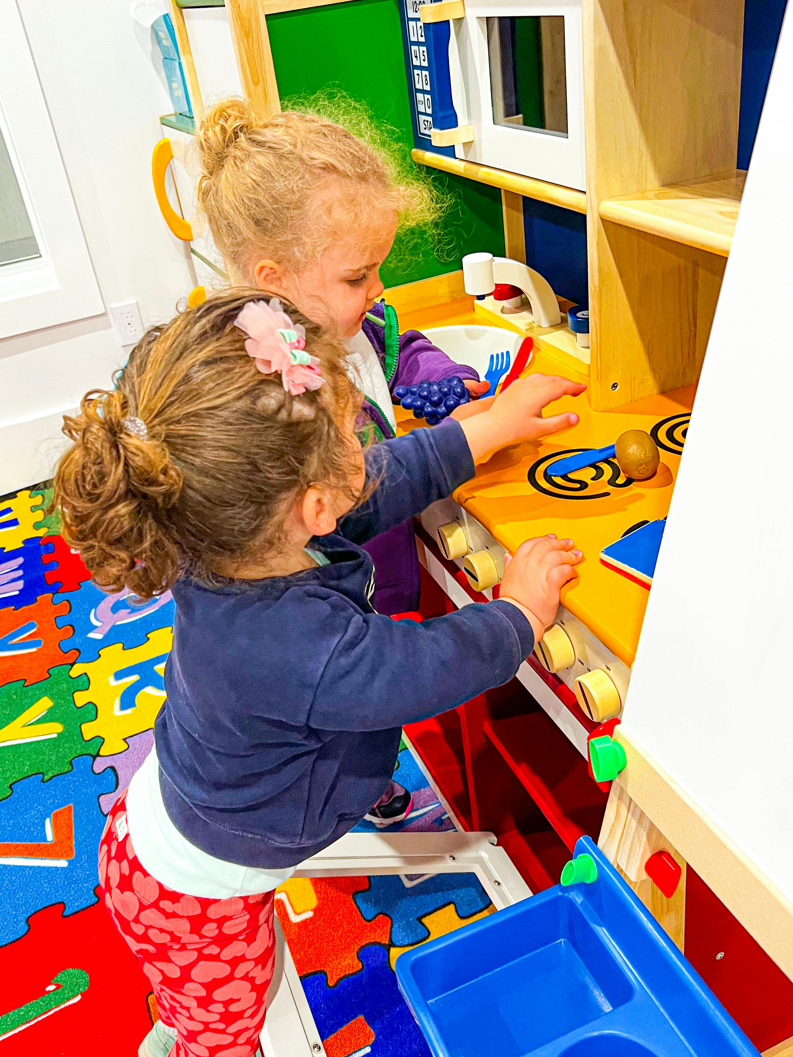 Two children playing with a toy kitchen set