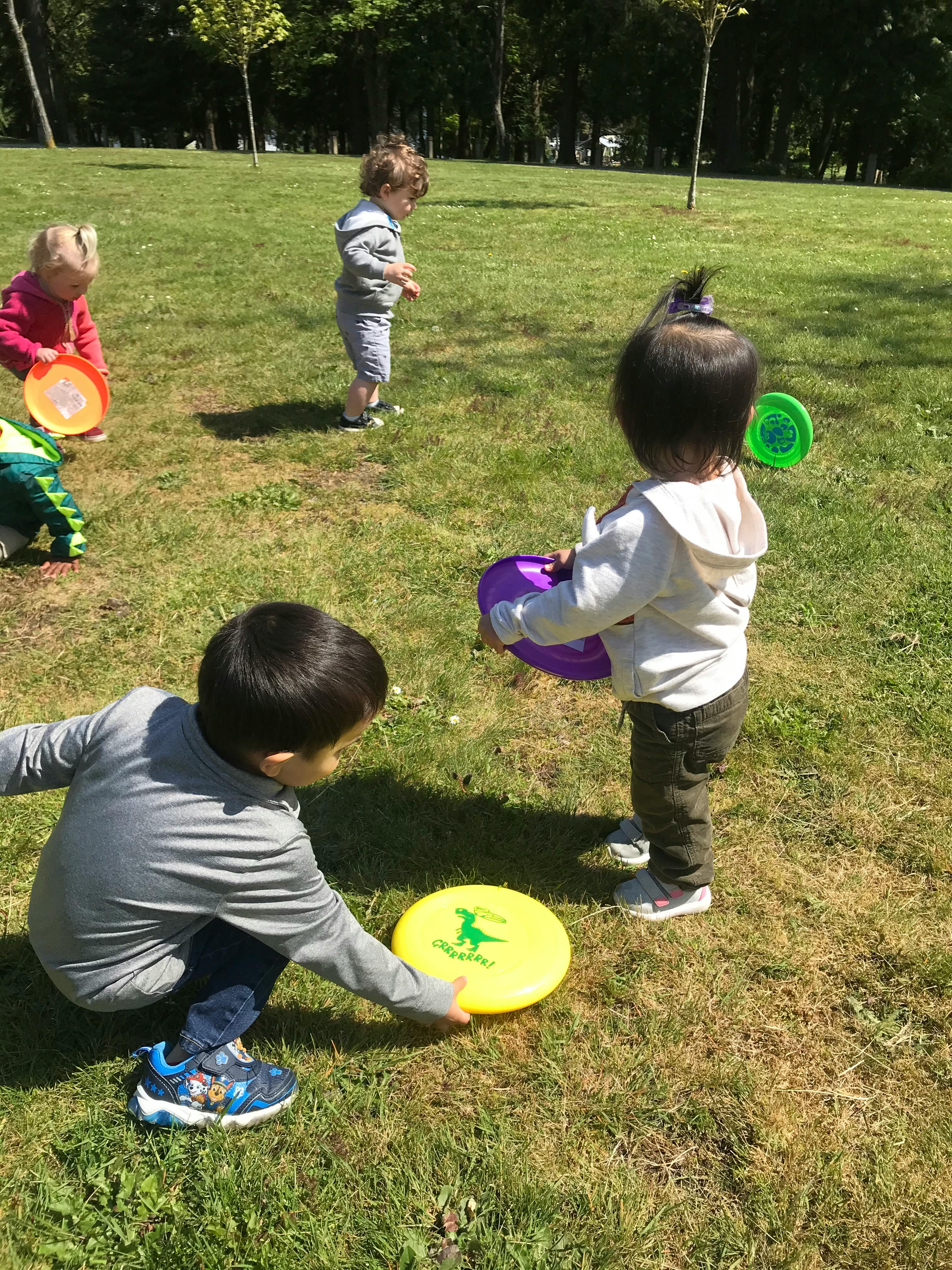 Children playing with frisbees on a grassy field